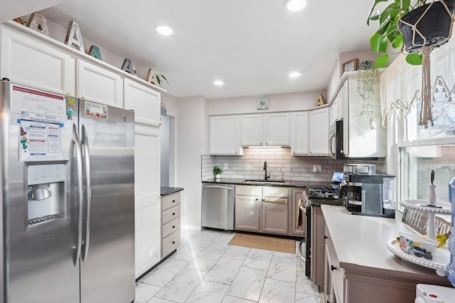 kitchen featuring white cabinets, backsplash, appliances with stainless steel finishes, and sink