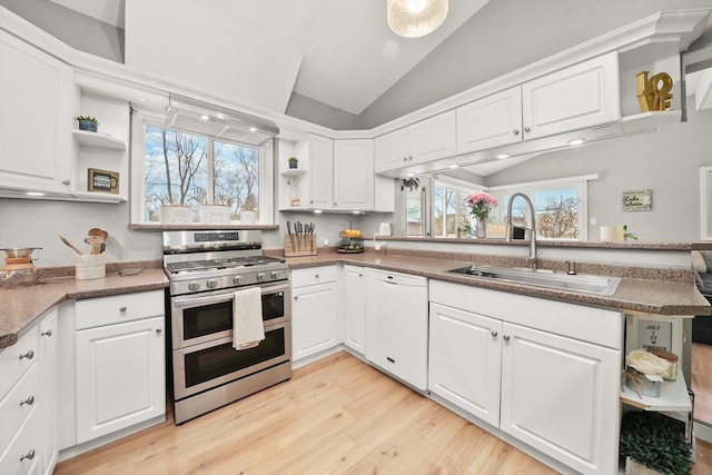 kitchen with white dishwasher, vaulted ceiling, sink, double oven range, and white cabinetry