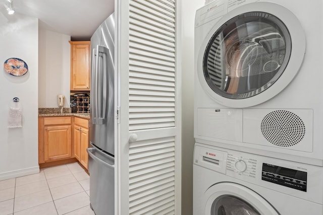 washroom with stacked washing maching and dryer and light tile patterned floors