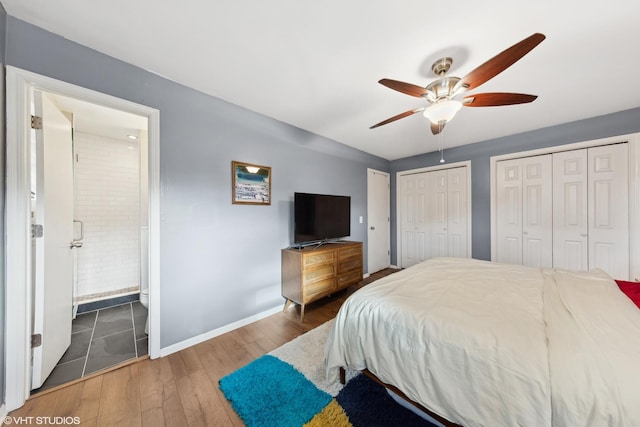 bedroom featuring ceiling fan, multiple closets, dark wood-type flooring, and ensuite bath