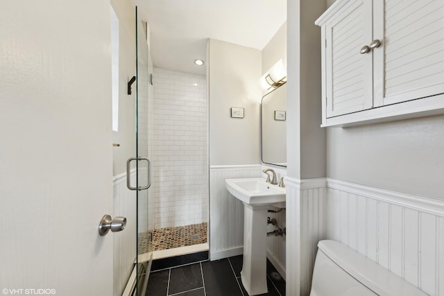 bathroom featuring tile patterned flooring, toilet, a shower with shower door, and sink