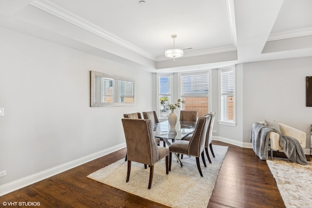 dining area with a raised ceiling, dark hardwood / wood-style floors, and ornamental molding