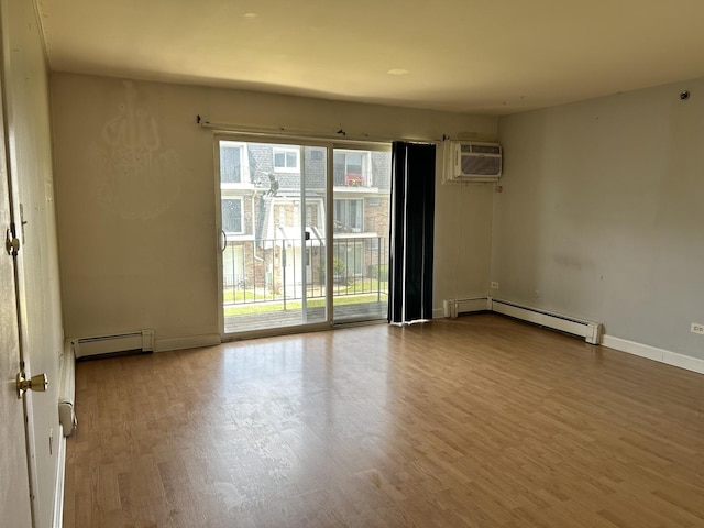 spare room featuring hardwood / wood-style floors, baseboard heating, and a wall mounted AC