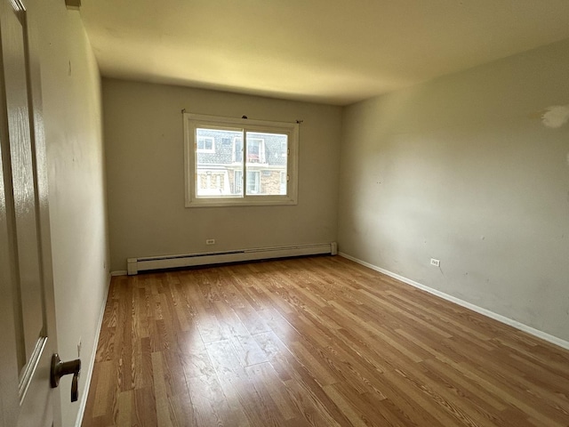 empty room with light hardwood / wood-style floors and baseboard heating