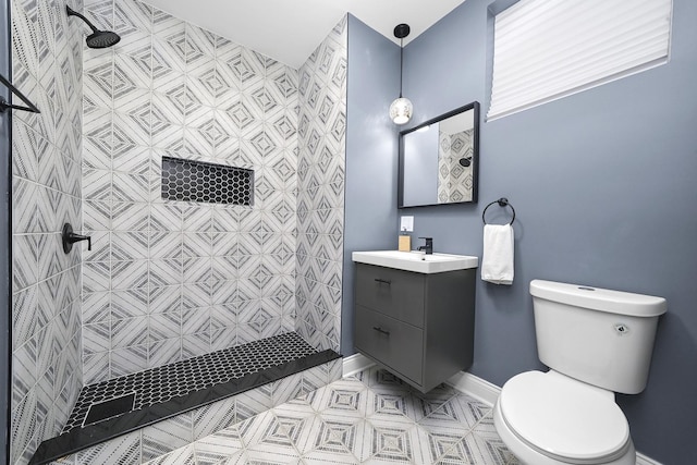 bathroom with tiled shower, vanity, and toilet