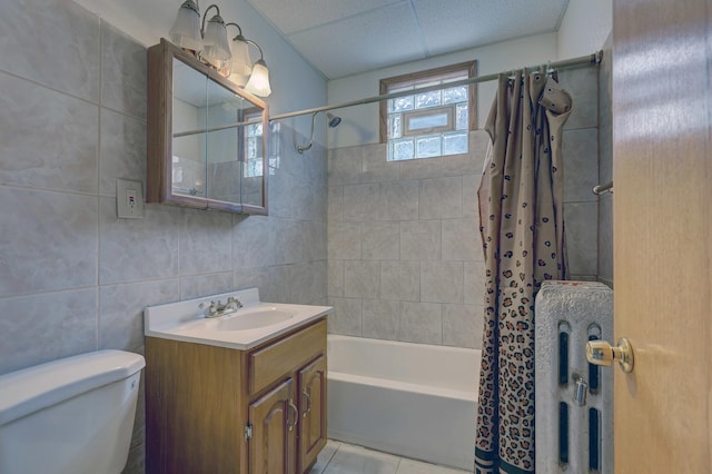 full bathroom with tile patterned flooring, toilet, shower / bath combo with shower curtain, vanity, and tile walls