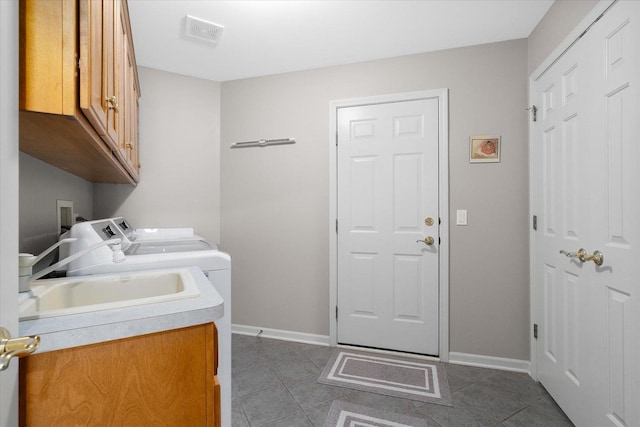 clothes washing area featuring dark tile patterned floors, cabinets, and washer and clothes dryer