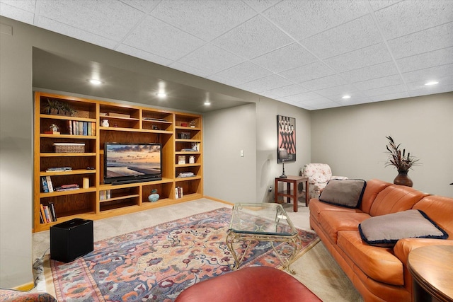 carpeted living room with a paneled ceiling and built in shelves