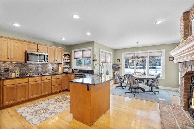 kitchen featuring appliances with stainless steel finishes, a notable chandelier, pendant lighting, a fireplace, and sink