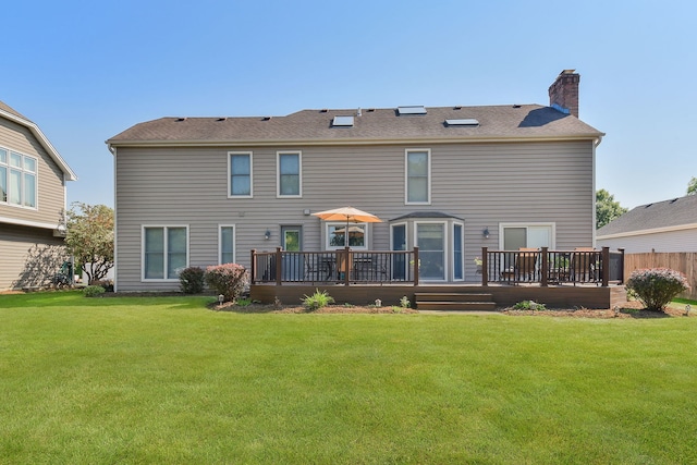 back of property with a yard and a wooden deck