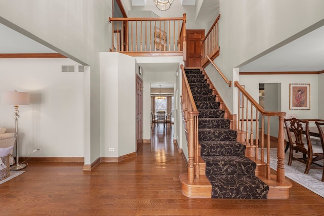 entryway featuring crown molding, hardwood / wood-style floors, a high ceiling, and an inviting chandelier