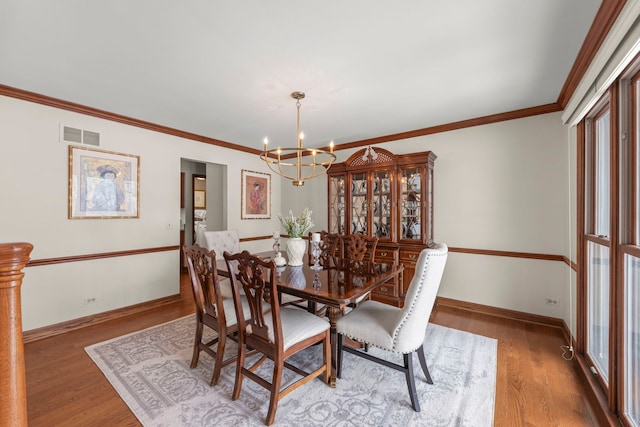 dining space featuring dark hardwood / wood-style flooring, crown molding, and a notable chandelier