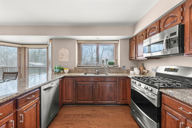 kitchen featuring dark hardwood / wood-style flooring, light stone countertops, sink, and stainless steel appliances