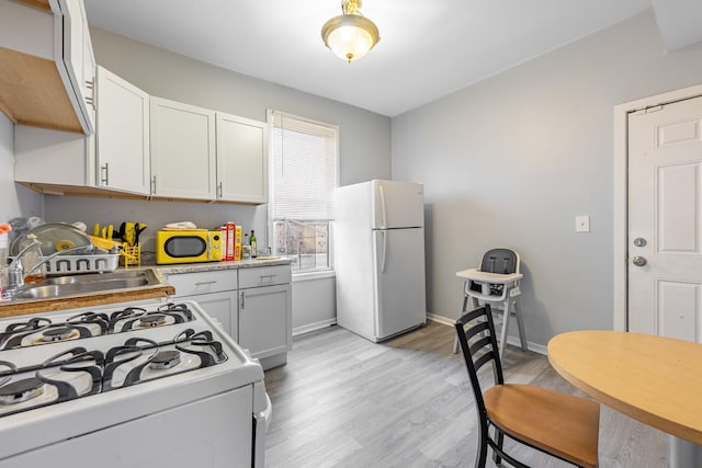 kitchen with white appliances, light hardwood / wood-style flooring, white cabinetry, and sink