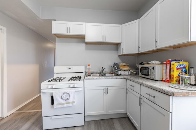 kitchen featuring sink, white cabinets, white appliances, and light hardwood / wood-style flooring