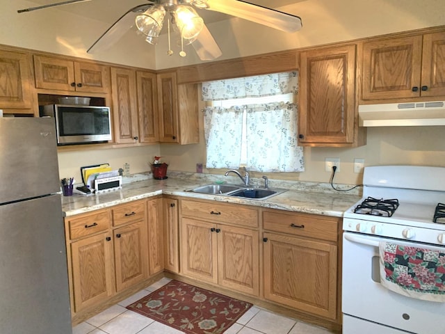 kitchen with ceiling fan, sink, stainless steel appliances, light stone counters, and light tile patterned floors