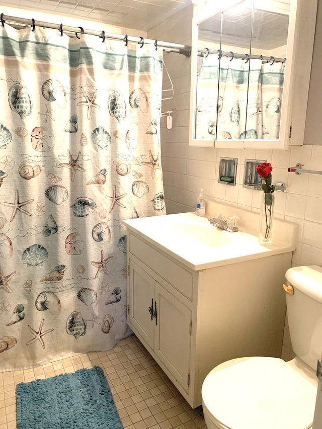 bathroom featuring tasteful backsplash, vanity, tile walls, tile patterned flooring, and toilet