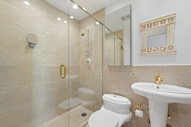 bathroom featuring backsplash, a shower with shower door, tile walls, and toilet