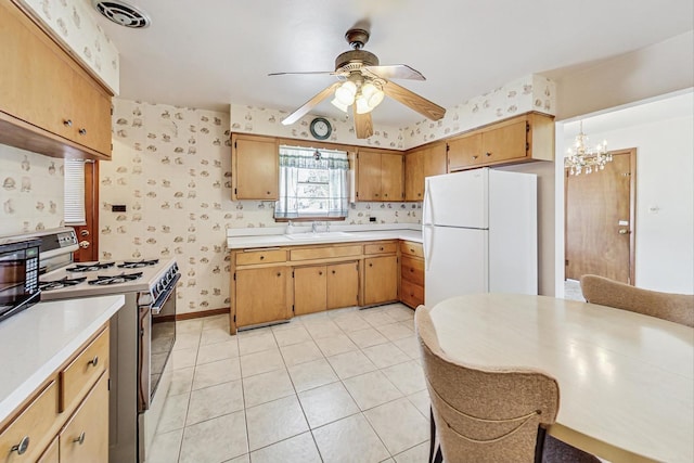 kitchen with ceiling fan with notable chandelier, pendant lighting, sink, light tile patterned floors, and white appliances