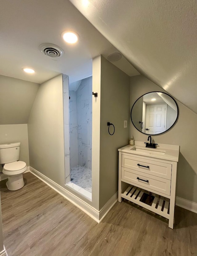 bathroom featuring hardwood / wood-style floors, vanity, walk in shower, and lofted ceiling