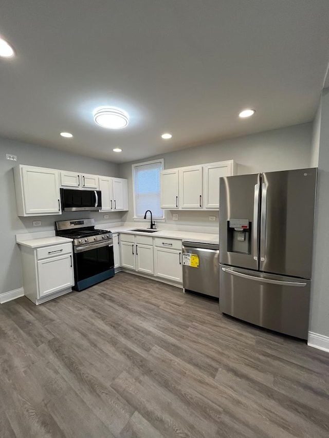 kitchen with white cabinets, sink, stainless steel appliances, and hardwood / wood-style floors