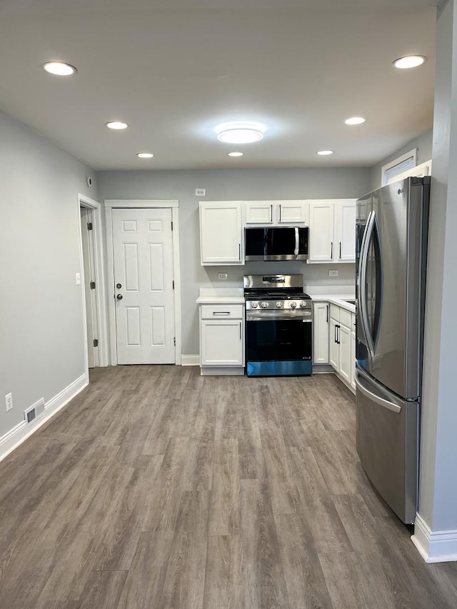 kitchen featuring stainless steel appliances, white cabinetry, and hardwood / wood-style flooring