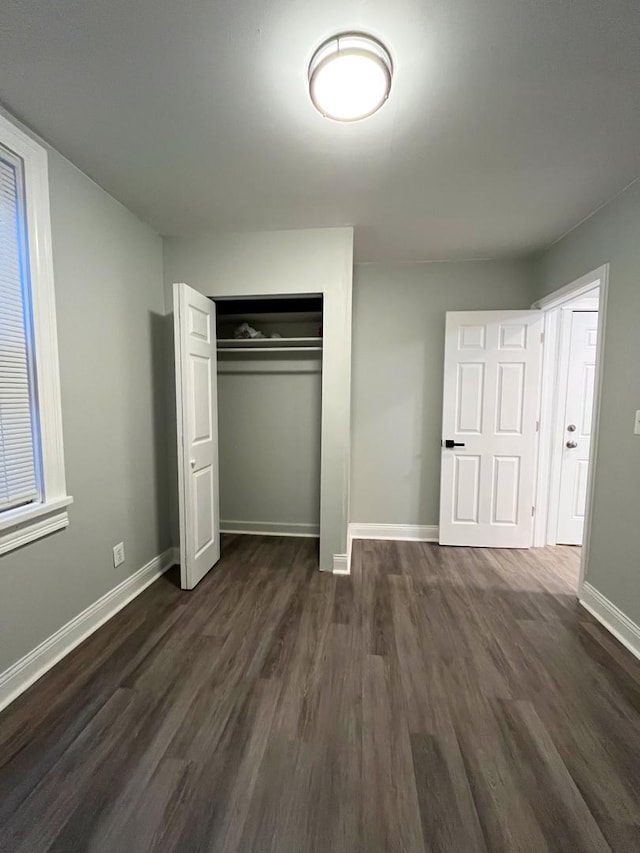 unfurnished bedroom featuring a closet and dark wood-type flooring