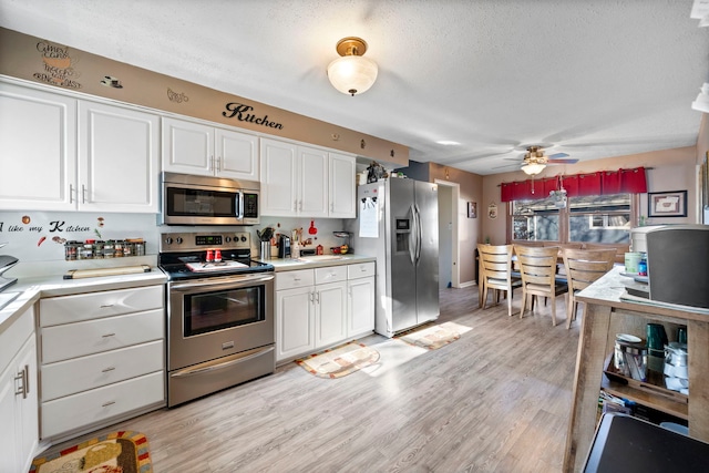 kitchen with a textured ceiling, light hardwood / wood-style floors, white cabinets, appliances with stainless steel finishes, and ceiling fan