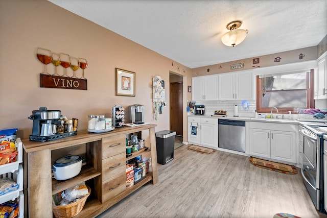 kitchen featuring tasteful backsplash, light wood-type flooring, white cabinetry, appliances with stainless steel finishes, and sink