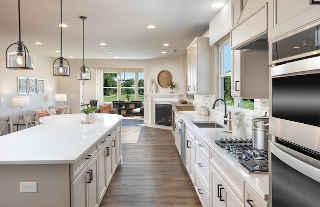 kitchen with pendant lighting, a center island, white cabinets, sink, and stainless steel appliances