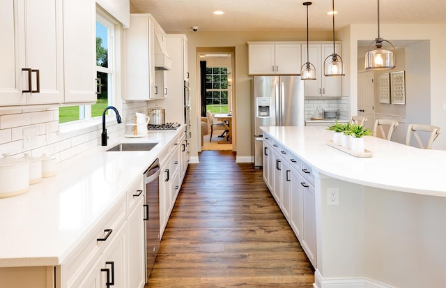 kitchen featuring white cabinets, a center island, sink, and hanging light fixtures