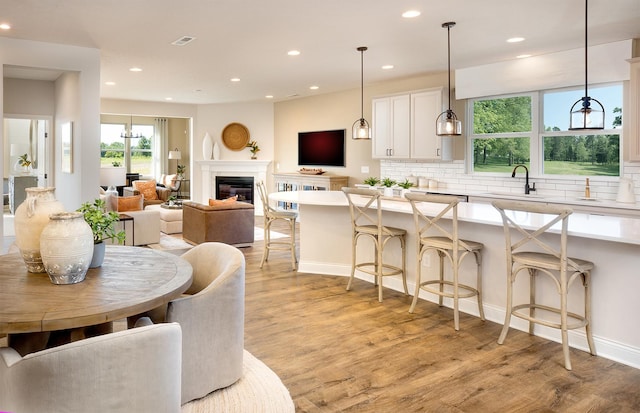 kitchen featuring a kitchen breakfast bar, light wood-type flooring, hanging light fixtures, and sink