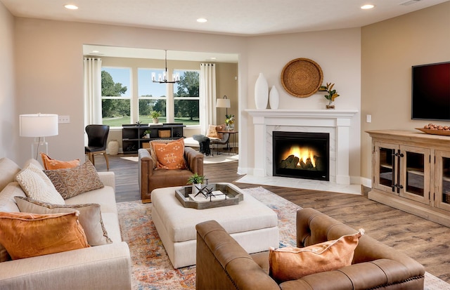 living room with a high end fireplace, a chandelier, and light hardwood / wood-style flooring