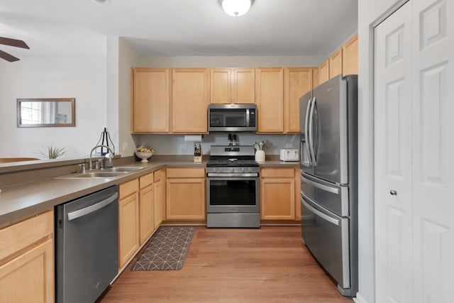 kitchen with appliances with stainless steel finishes, light brown cabinetry, ceiling fan, sink, and light hardwood / wood-style flooring