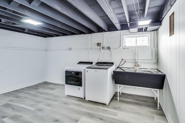 laundry room with light hardwood / wood-style floors, sink, and washer and dryer