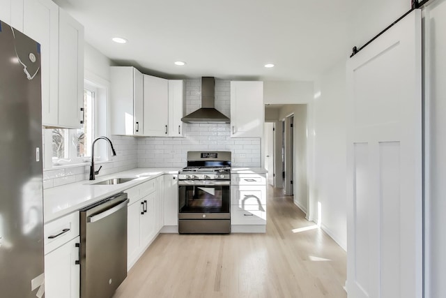 kitchen featuring sink, white cabinets, wall chimney exhaust hood, and appliances with stainless steel finishes