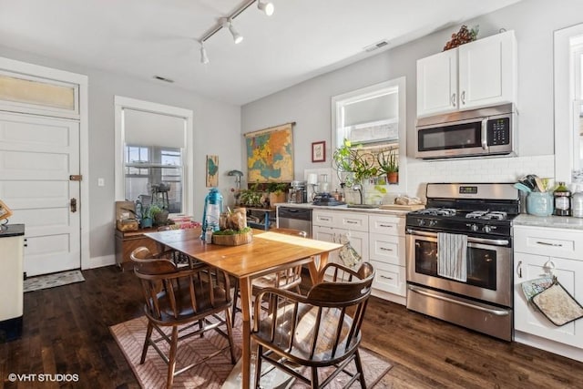 kitchen featuring white cabinets, backsplash, appliances with stainless steel finishes, and dark wood-type flooring