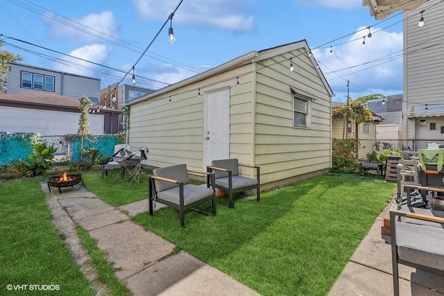 view of outbuilding with a fire pit and a lawn