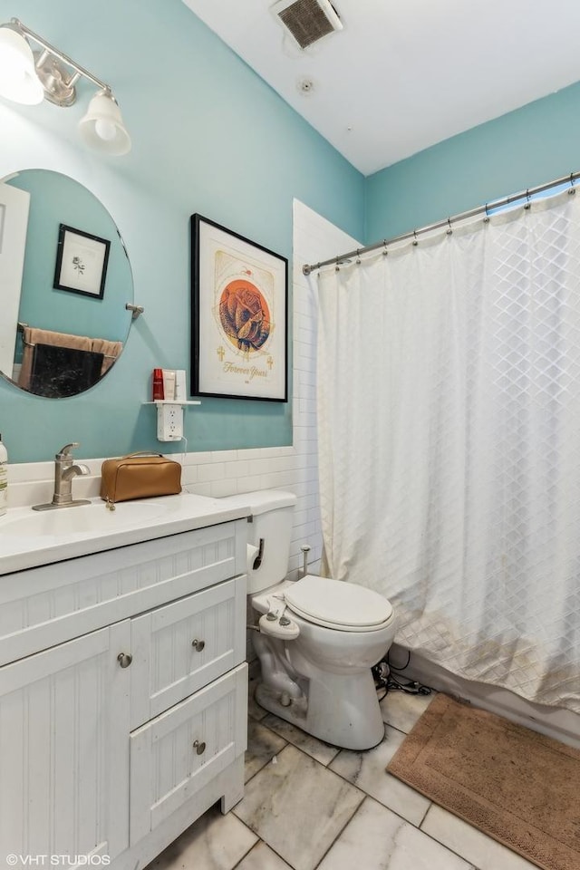 full bathroom with vanity, shower / tub combo with curtain, tile walls, tile patterned flooring, and toilet