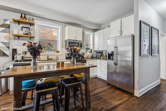 kitchen with decorative backsplash, appliances with stainless steel finishes, and white cabinetry