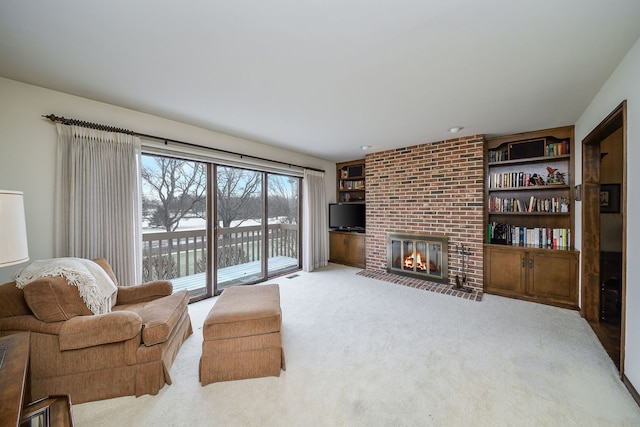 living room featuring light carpet, built in features, and a fireplace