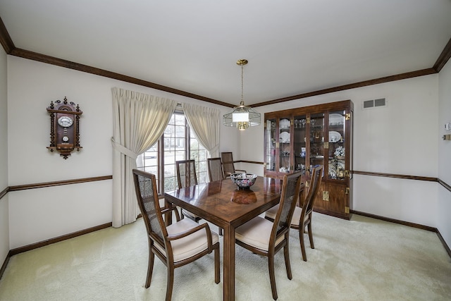 dining space featuring crown molding, a chandelier, and light colored carpet