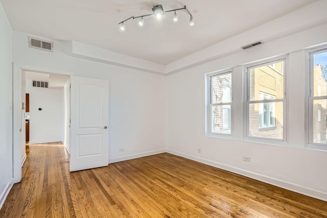 empty room with a wealth of natural light and hardwood / wood-style floors