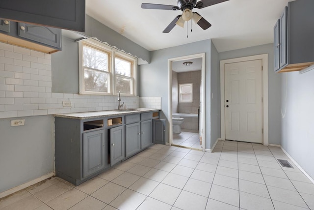 kitchen with light tile patterned floors, ceiling fan, gray cabinetry, and sink