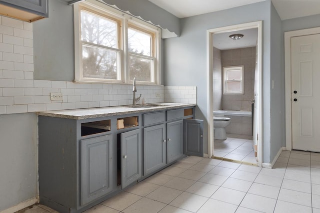 kitchen featuring gray cabinetry, light tile patterned flooring, and sink