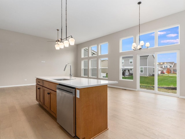 kitchen featuring pendant lighting, sink, a kitchen island with sink, a chandelier, and stainless steel dishwasher