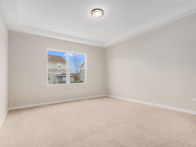 carpeted spare room with a raised ceiling