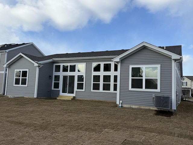 back of house with central air condition unit and a yard