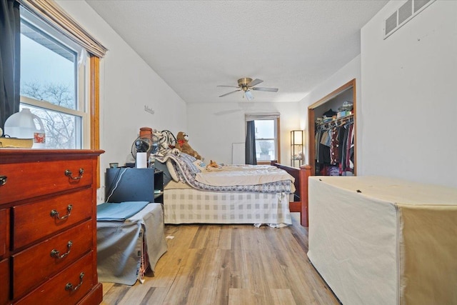 bedroom featuring a textured ceiling, light hardwood / wood-style floors, a closet, and ceiling fan