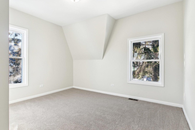 carpeted spare room featuring vaulted ceiling and a wealth of natural light